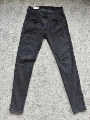 Replay Jeans  - Säljer ett par svarta skinny jeans från replay med slitna detaljer, jeansen har en smal passform. Har använt dom 2 gånger innan så dom är helt nya. Dom har storlek: W:28 L:30