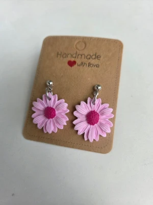 Handgjorda örhängen - rosa prästkragar  - Supersöta handgjorda örhängen i form av rosa prästkragar med mörkrosa mitt. Örhängena har silverfärgade kulstift och är tillverkade för hand av mig i polymerlera.