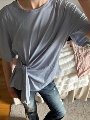 Ljusblå t-shirt med knyt i sidan - Säljer denna fina blåa tröja med knyte som är köpt här på Plick! Jättefin och skönt material☺️💙