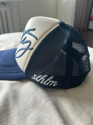 Trucker keps  - Navy / creme white trucker keps, ”vanity” puffprint på framsidan med broderat ”sthlm” på sidan