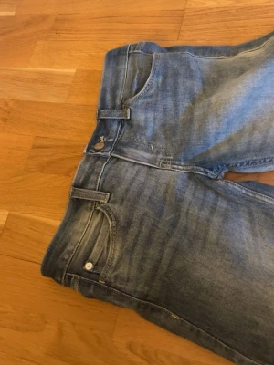 Blå bootcut jeans från cheap monday - Säljer ett par blå bootcut jeans med snygga detaljer. Storlek 27/34