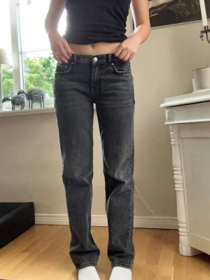 Svarta raka jeans med hög midja - Säljer ett par svarta raka jeans med låg midja och klassisk femficksmodell. Jeansen har en avslappnad passform och är tillverkade i denim. Perfekta för dig som gillar en enkel och stilren look.