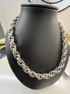 Tjockt silverfärgat kedjehalsband - Säljer ett chunky halsband i silverfärgad metall med tvinnad kedjedesign. Halsbandet har en robust och modern look med stora, tätt sammanlänkade länkar som ger ett statement-intryck. Perfekt för dig som gillar att sticka ut med accessoarer.