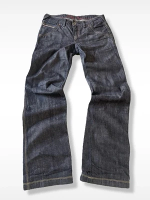 Raw bootcut jeans Hilfiger Denim - Fint skick, modell från 2006, väldigt sällsynta, storlek W31 L34.  Mått:  * Midja: 42 cm * Längd: 107 cm * Benöppning: 24 cm  (Måtten kan variera någon centimeter.)  Märke: Tommy Hilfiger.