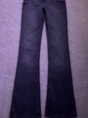 Gråa bootcut jeans från ONLY - Säljer ett par gråa bootcut jeans från ONLY med klassisk femficksmodell och knapp med logga. Jeansen har utsvängda ben och är tillverkade i ett mjukt denimtyg som sitter snyggt. Inte använda många gånger, skriv vid intresse skickar samma dag eller dagen efter!