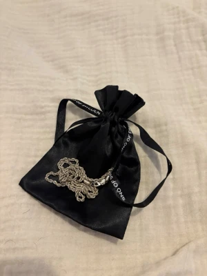 SILVERHALSBAND från Snö of Sweden - Säljer ett stilrent halsband i silverfärg från Snö of Sweden. Kedjan har en tvinnad design som ger ett snyggt och modernt intryck. Perfekt accessoar för att lyfta din outfit. Levereras i en svart tygpåse med logga. Den är i rostfritt stål. 
