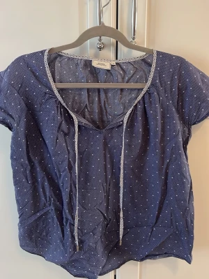 Blå mönstrad Blus  - En blus i storlek 38 köpt secondhand från boomerang som är blå mönstrad med snören som är metallklädda i toppen. Super fin till sommaren.