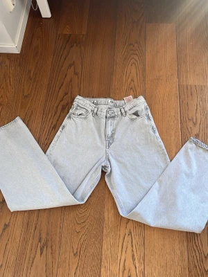 Ljusblå raka jeans/ baggy fit - Säljer ett par ljusblå jeans med rak passform och hög midja. Klassisk femficksmodell med bälteshällor och knappgylf. Jeansen är i ett mjukt denimtyg som ger en avslappnad look. Perfekta till sneakers eller boots.