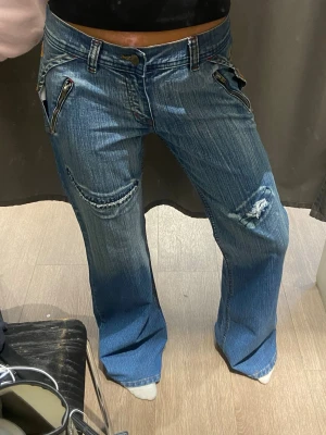 Instresse koll på mina Blå jeans från Dolce &gabanna - Undrar om nån hade varit intresserad av att köpa mina blå jeans från D&G med vida ben och coola dragkedjedetaljer vid fickorna. Jeansen har slitningar på ena benet och kontrastsömmar. Jeansen hade passat på S loose och m loose men närmare botcut. Bak finns en tydlig D&G-logga på linningen. Perfekta för dig som gillar en avslappnad men edgy stil.