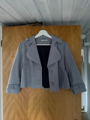 Croppad kappa - grå kort kappa med stora knappar och fina detaljer. 