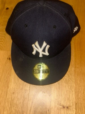 New Era Yankees 59FIFTY keps marinblå - Snygg marinblå New Era 59FIFTY keps med klassiskt New York Yankees broderat vitt logotyp framtill. Kepsen har rak skärm och New Era-logga på sidan. Tillverkad i ett tåligt tygmaterial som ger en clean och sportig look.