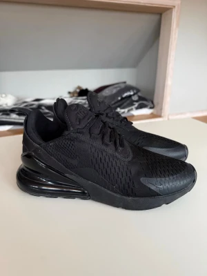Svarta Nike Air Max 270  - Säljer ett par helsvarta Nike Air Max 270 sneakers med mesh-överdel och stor synlig Air-enhet i hälen. Bättre pris med snabbaffär 