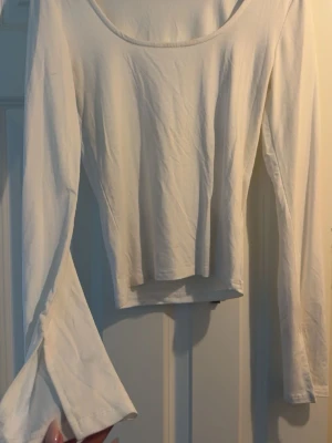 Vit långärmad topp med slit på armen  - En enkel vit långärmad topp med rund halsringning och slit på armen. Har använt en gång.