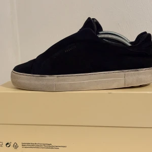 Svarta sneakers från Axel Arigato - Snygga svarta sneakers från Axel Arigato i mocka med vit platt sula. Minimalistisk design med diskret logga på sidan och rund tå. Perfekta för dig som gillar stilrena och trendiga skor med premiumkänsla. Lite sönder i sulan men anväd bara kolla bild 5 pris kan diskuteras 