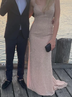 Glittrig champagnefärgad balklänning  - Säljer min fina balklänning i champagnefärg med tunna axelband och öppen rygg. Klänningen är täckt av glittriga detaljer och har en figurnära passform som ger en snygg siluett. Några få paljetter har ramlat av men inget man tänker på💕nypris 1700kr