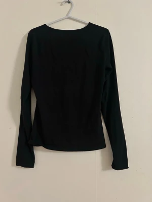 Svart långärmad topp från H&M - En enkel svart långärmad topp från H&M med rund halsringning. Toppen har en klassisk passform och är tillverkad i mjuk bomull, perfekt att styla till olika outfits.