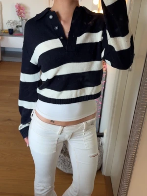 Mörkblåvit randig stickad tröja - Säljer en mörkblå och vit stickad tröja från H&M:s Divided-kollektion. Tröjan har breda horisontella ränder, krage med knappar och långa ärmar