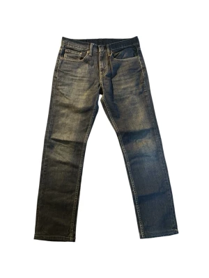 Levi's raka blå jeans | 511 | W31 L32 - Säljer ett par klassiska raka jeans från Levi's i en tvättad blå färg med slitningar. Jeansen har fem fickor, gylf med dragkedja och knapp samt den ikoniska läderpatchen bak i midjan. Materialet är robust denim i bomull.