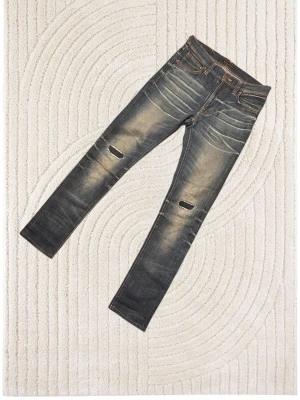 Slim jeans från Nudie Jeans med slitningar - Snygga slim fit jeans från Nudie Jeans i mörkblå tvätt med slitningar och hål på knäna. Klassisk femficksmodell med orange sömmar och Nudie-logga på bakfickan. Perfekta för en avslappnad och trendig look.