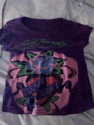 Lila Ed Hardy t-shirt - Snygg lila t-shirt från Ed Hardy i barnstorlek så det är typ storlek 140/150. Den sitter som en crop top eftersom det är barnstorlek så typ xxs/xs. 