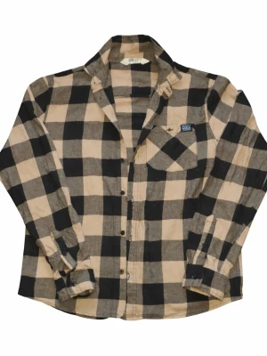 Rutig skjorta från H&M i beige och svart - Klassisk rutig skjorta från H&M i beige och svart med stora rutor. Skjortan har lång ärm, bröstficka och knappar framtill. Perfekt för en avslappnad, trendig look och känns skön mot huden.