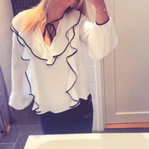 Vit blus med svarta detaljer  - Säljer denna vita blus med fina svarta detaljer från H&M som inte kommer till användning. Blusen är endast använd en gång så inga tecken på skador eller liknande!!