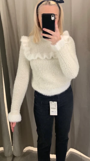 Vit fluffig stickad tröja med volang ifrån Zara - Supermjuk vit stickad tröja med volangdetalj över bröstet och axlarna. Köpt ifrån Zara och helt oanvänd. 