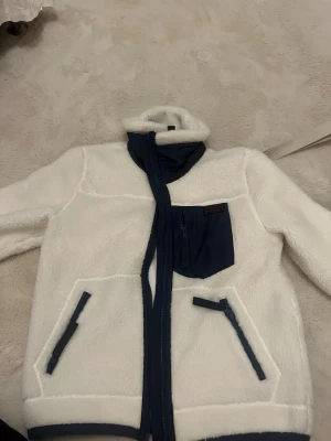 Ralph lauren Vit teddyjacka med blå detaljer - Ralph lauren storlek S, aldrig använd. Vit med marinblåa detaljer.