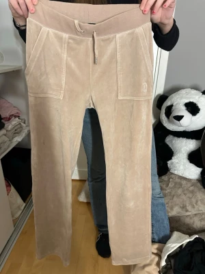 Beiga velourmjukisbyxor Juicy Couture - Snygga beiga mjukisbyxor i velour från Juicy Couture. Finns lite fläckar som ej går bort i tvätten men inget man tänker på