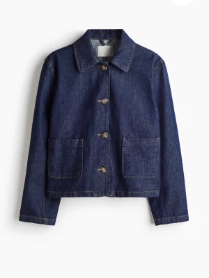 Mörkblå klassisk jeansjacka - Snygg mörkblå jeansjacka med raka linjer och stora framfickor. Jackan har knäppning med fyra metallknappar och en enkel krage. Perfekt basplagg för dig som gillar en clean och tidlös look.