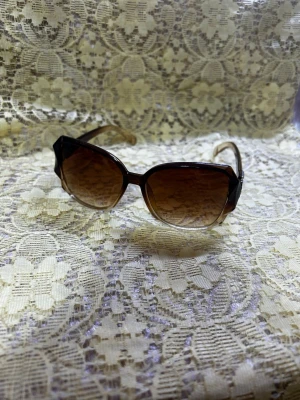 Bruna fyrkantiga solglasögon - Snygga solglasögon med fyrkantig form och bruna tonade glas. Bågarna är i transparent brun plast med silverfärgade detaljer vid gångjärnen. Perfekta för dig som vill ha en trendig accessoar med retrovibbar.