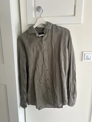 Grön linneskjorta från Massimo Dutti - Säljer en stilren grön skjorta från Massimo Dutti i 100% linne. Skjortan har klassisk krage, knappar framtill och långa ärmar. Perfekt för dig som gillar en avslappnad men ändå snygg look.