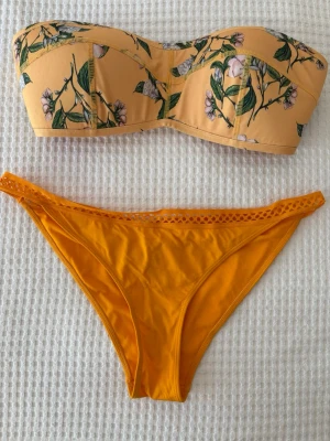 Bikini set - Snygg bandeau bikini från H&M i gul nyans. Överdelen  storlek 42. Bikinitrosa storlek 40. Perfekt för soliga dagar på stranden eller vid poolen.