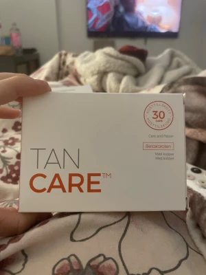 Tan Care kosttillskott 30 kapslar - Tan Care är ett kosttillskott med 30 kapslar som innehåller betakaroten och koppar. Produkten är framtagen för att bidra till normal hudpigmentering och bibehålla normal hud. Förpackningen är vit med orange text och har tydliga instruktioner på baksidan. Man blir brun om man tar en sån kapsel varje dag en gång om dagen i 30 dagar.