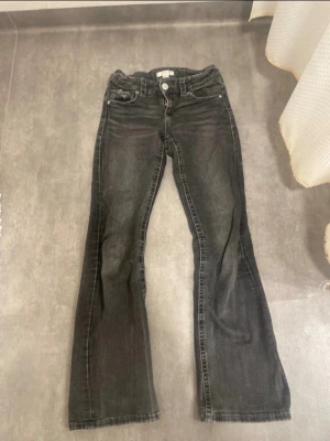 Svarta bootcut jeans med låg midja - Säljer ett par svarta bootcut jeans med låg midja och klassisk femficksdesign. Har använt en del men de är fortfarande i bra skick. Fläckar kan synas på bild, men kommer tvättas bort 