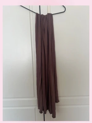 Ljusbrun sjal - En stilren ljusbrun sjal. Sjalen är lång och luftig, perfekt att svepa runt halsen för en avslappnad look. Tillverkad i ett tunt, mjukt tyg som ger ett snyggt fall. Enkel att matcha med olika outfits. 💞