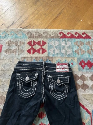 Svarta lågmidjade true religion jeans - Säljer ett par skitsnygga lågmidjade true religion byxor som tyvärr aldrig kommit till användning då jag tänkte sy om dem men aldrig orkade…😢 Mått:  Rakt över midjan: 38cm Innerbenslängd: 82cm Full längd: 103cm Rakt över låret: 23cm