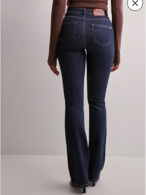 Mörkblå bootcut jeans från ONLY - Snygga mörkblå bootcut jeans från ONLY med hög midja och klassiska bakfickor. Jeansen har en figurnära passform upptill och utsvängda ben. Tillverkade i stretchigt denim för extra komfort. Helt nya använd bara en gång . Nypris :459 kr