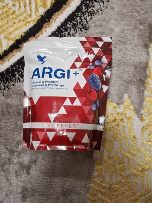 Forever ARGI+ kosttillskott - Säljer en påse ARGI+ från Forever, ett kosttillskott med L-arginin och vitaminer. Förpackningen är röd och vit med geometriskt mönster och bärmotiv. Innehåller bland annat vitamin C, D, B6, B12 och folsyra. Perfekt för dig som vill boosta din vardag.
