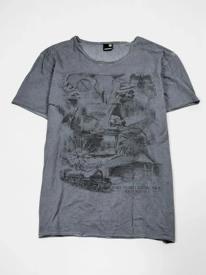 Grå t-shirt med tryck från Cheap Monday - Snygg grå t-shirt från Cheap Monday med unikt svart tryck framtill som visar olika motiv och text. T-shirten har rund halsringning och korta ärmar. Perfekt för dig som gillar streetwear och vill ha något som sticker ut.