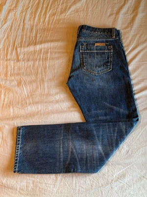 Jeans New Zealand Auckland - Klassiska blå jeans från N.Z.A (New Zealand Auckland) med raka ben. Storlek: W34 L34. Måtten: Midja - 44 cm Längd - 106 cm Innerbenslängd - 81 cm Fotöppning - 19.5 cm Lår - 32 cm