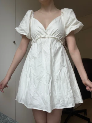 Vit kort puffärmad klänning - Söt vit kortklänning med puffärmar och v-ringning. Ny skick med lapparna kvar. Köpt från Nelly men hann inte lämna tillbaka den därför säljer jag vidare☺️
