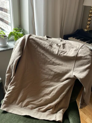 Beige sweatshirt Weekday - En basic beige sweatshirt i mjuk bomull med rund halsringning och ribbade muddar vid ärmslut och nederkant. Perfekt för en avslappnad och stilren look. Passar till jeans eller mjukisbyxor.