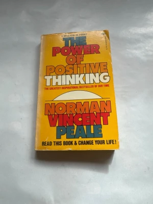 The Power of Positive Thinking bok - Säljer boken 'The Power of Positive Thinking' av Norman Vincent Peale. Omslaget är gult med stora röda och blå bokstäver. Perfekt för dig som gillar självhjälpsböcker och personlig utveckling.