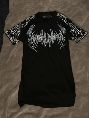 Breathe divinity compressionshirt vit och isblå mönster  - Säljer en svart träningströja från breathe divinity med vita och isblåa grafiska tryck på både fram- och baksidan samt på ärmarna. T-shirten har korta ärmar och en liten pass form vilket gör att den passar en medium person också. Använd en gång