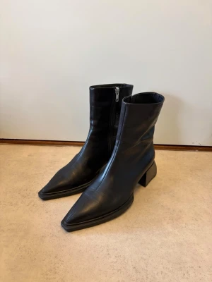 Svarta ankelboots från Vagabond, strl 37 - Svarta ankelboots från Vagabond, strl 37. Stilren modell med spetsig tå, stabil klack och dragkedja på sidan. Tillverkade i läder. Använda men i fint skick (se bilder). Perfekta till både vardag och fest. Nypris ca 2000 kr. Pris: 1199 kr – kan diskuteras vid snabb affär.  