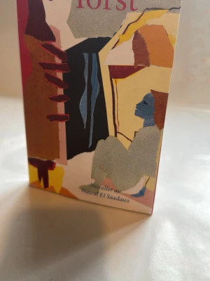 Törst av Nawal El Saadawi - Säljer boken 'Törst' av Nawal El Saadawi. Omslaget har ett färgstarkt, abstrakt collage i nyanser av gult, blått, rött och beige. Boken är i pocketformat och innehåller noveller. Perfekt för dig som gillar tankeväckande skönlitteratur.