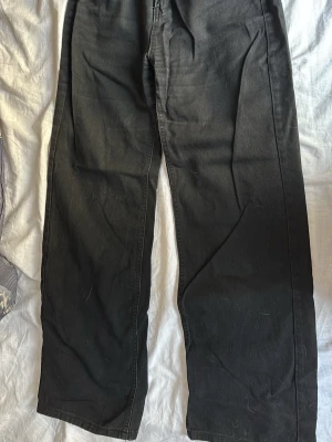 Svarta raka jeans - Säljer ett par svarta jeans med rak passform och klassisk femficksdesign. Jeansen har hög midja och är tillverkade i ett kraftigare denimtyg. Perfekta för en avslappnad och stilren look.