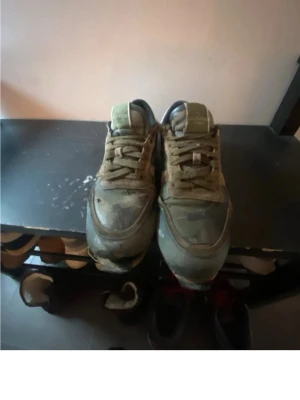 Olivgröna camo sneakers Calvin Klein - Säljer ett par olivgröna sneakers från Calvin Klein med camomönster. Skorna har klassisk låg profil, rund tå och snörning framtill. Materialet är en mix av textil och mocka, vilket ger en schysst streetkänsla.