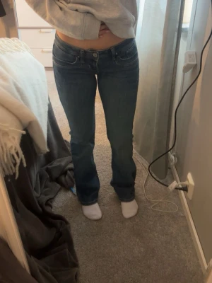 Mörkblå bootcut jeans - Storlek 25/30 Säljer ett par mörkblå bootcut jeans med klassisk femficksdesign och låg midja. Jeansen har en snygg tvätt och sitter tajt över låren för att sedan bli vidare nedtill. Perfekta för dig som gillar en avslappnad men ändå trendig look.